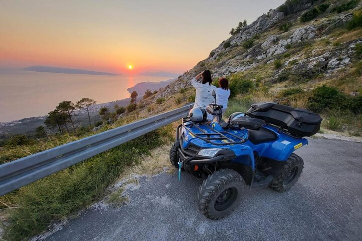 two people sitting on a atv on the side of a road