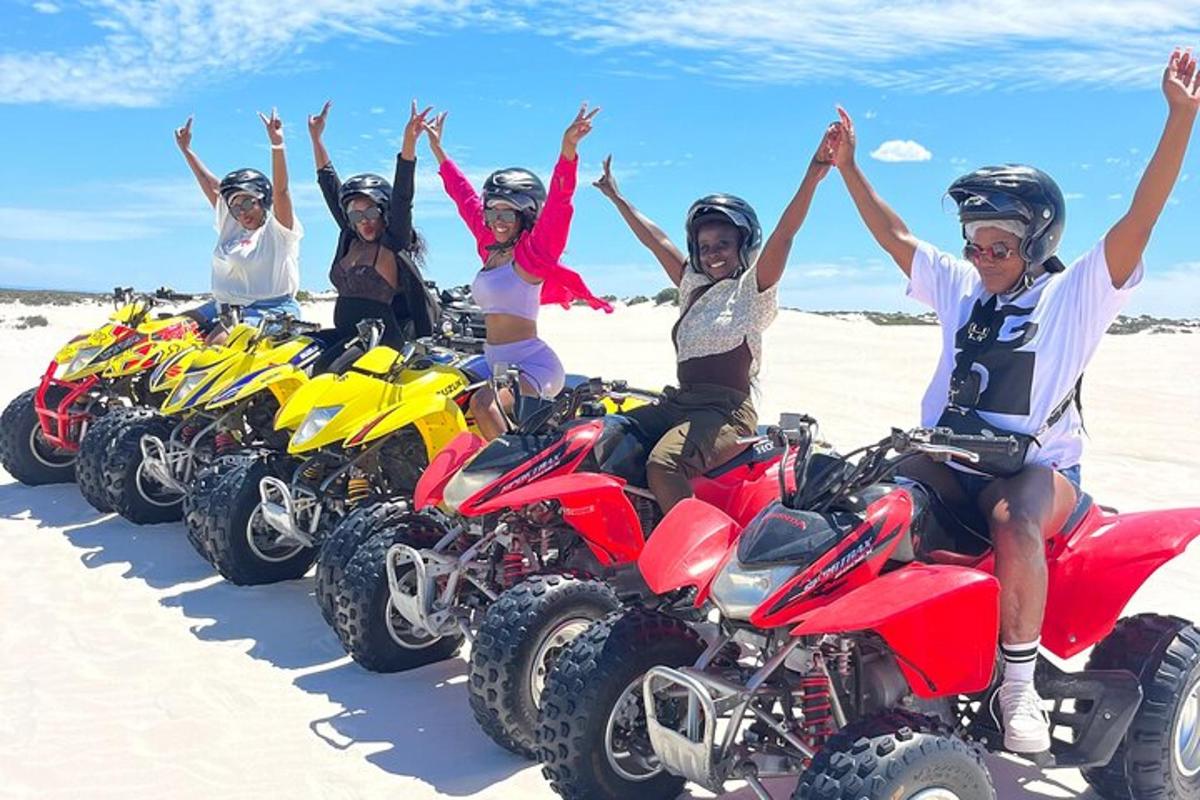 Un grupo de personas sentadas en vehículos todo terreno en la playa.
