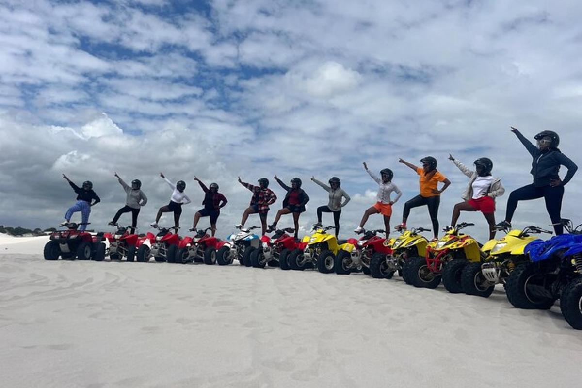 Un grupo de personas de pie en motocicletas en la arena.