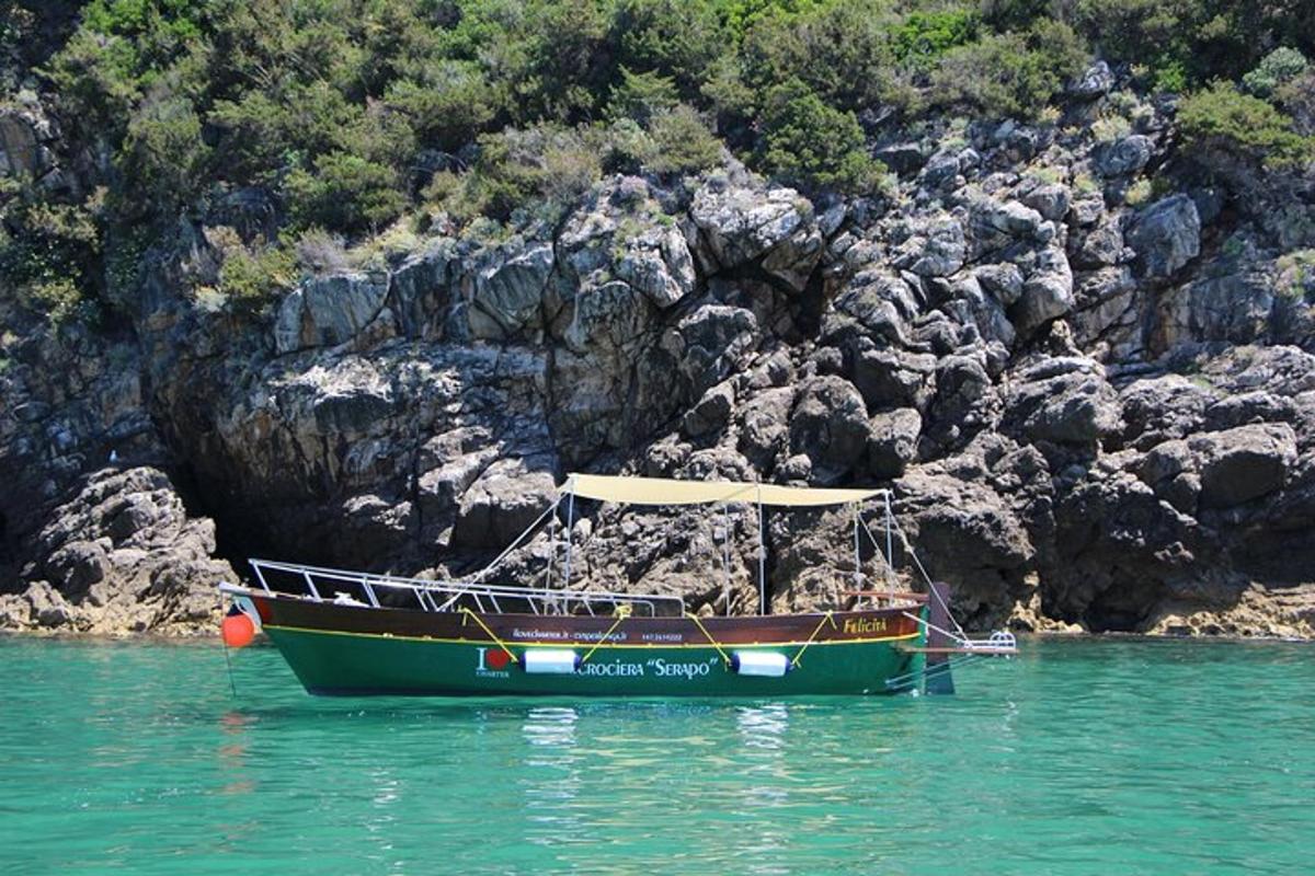 a boat sitting in the water next to a rocky hill