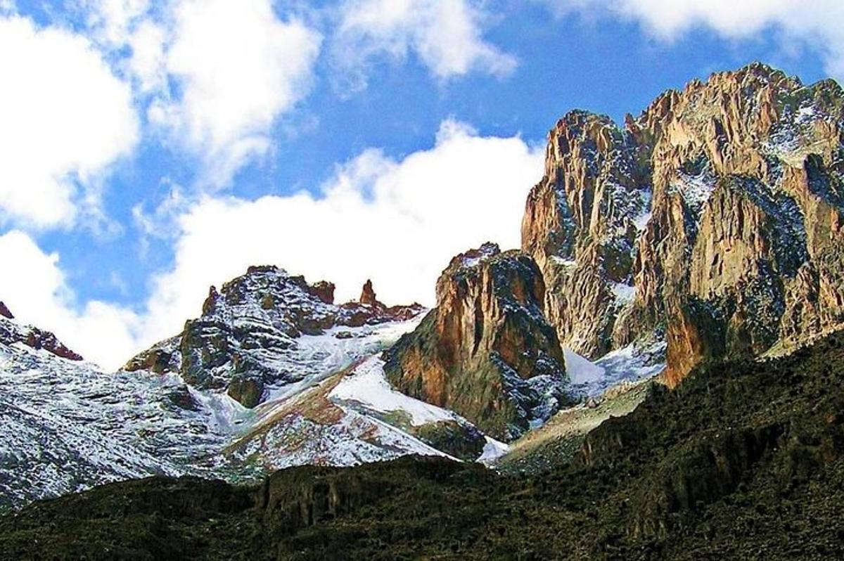 gunung berbatu dengan salju di atasnya dan awan di langit