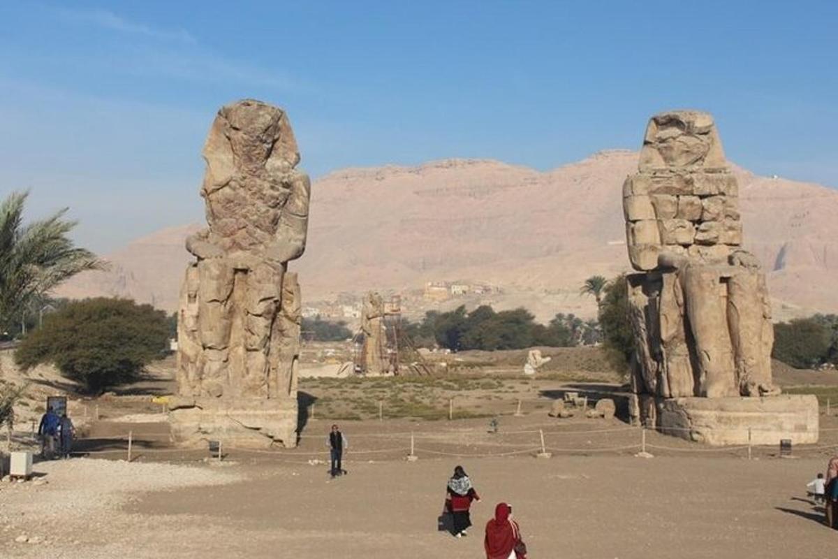 μια ομάδα ανθρώπων που περπατούν κοντά σε δύο μεγάλα πέτρινα αγάλματα