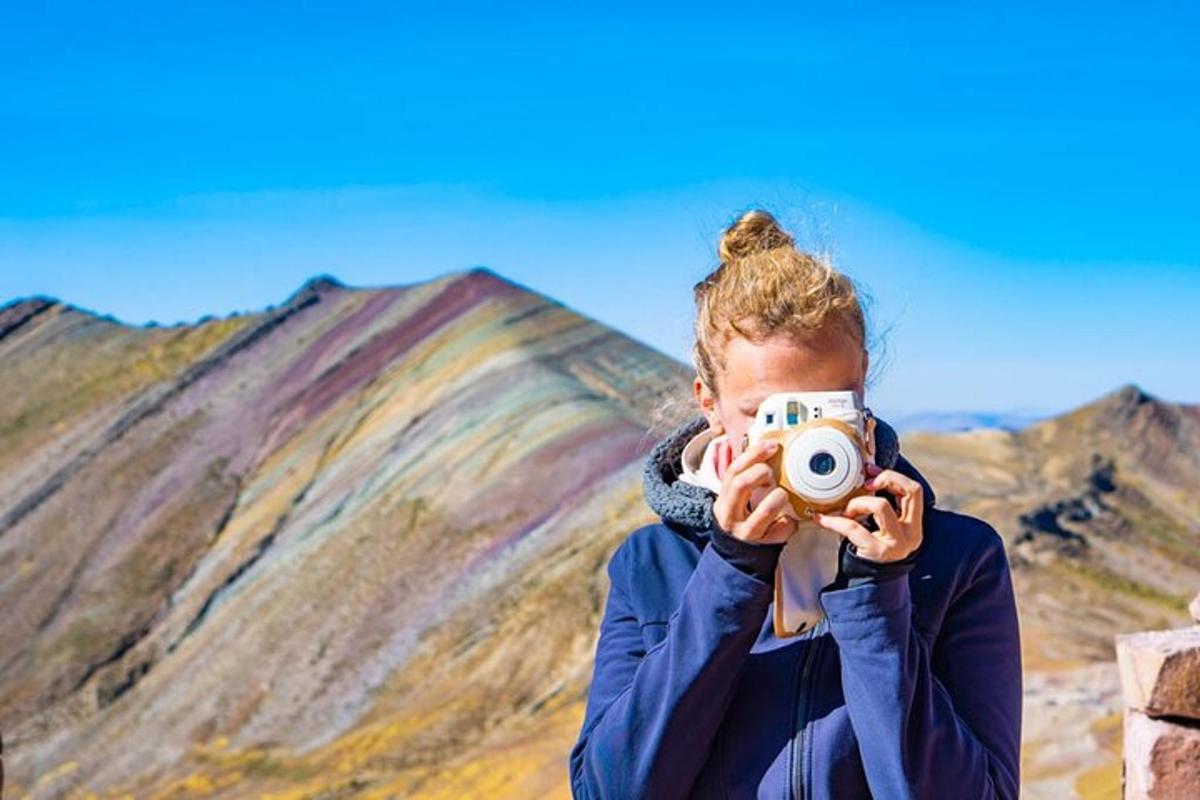 kona heldur á myndavél fyrir framan fjall
