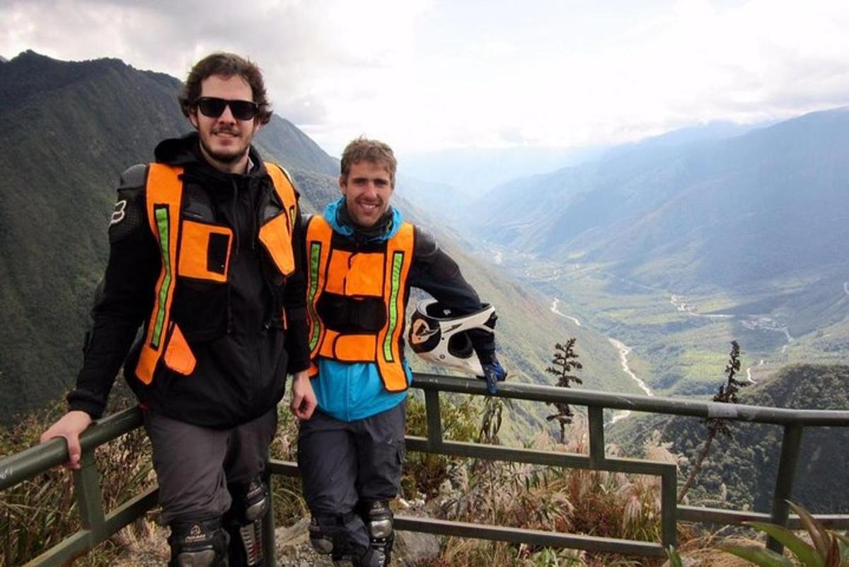two men wearing life jackets standing on top of a mountain