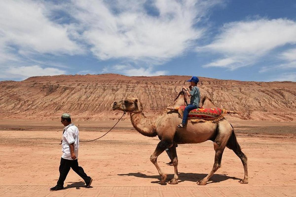 um homem conduzindo uma pessoa montada em um camelo no deserto