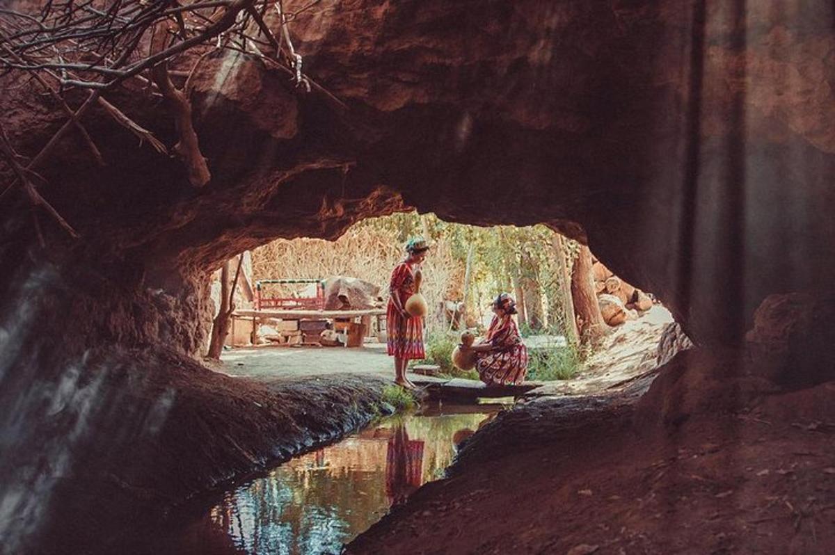 uma pintura de duas pessoas em pé em uma caverna