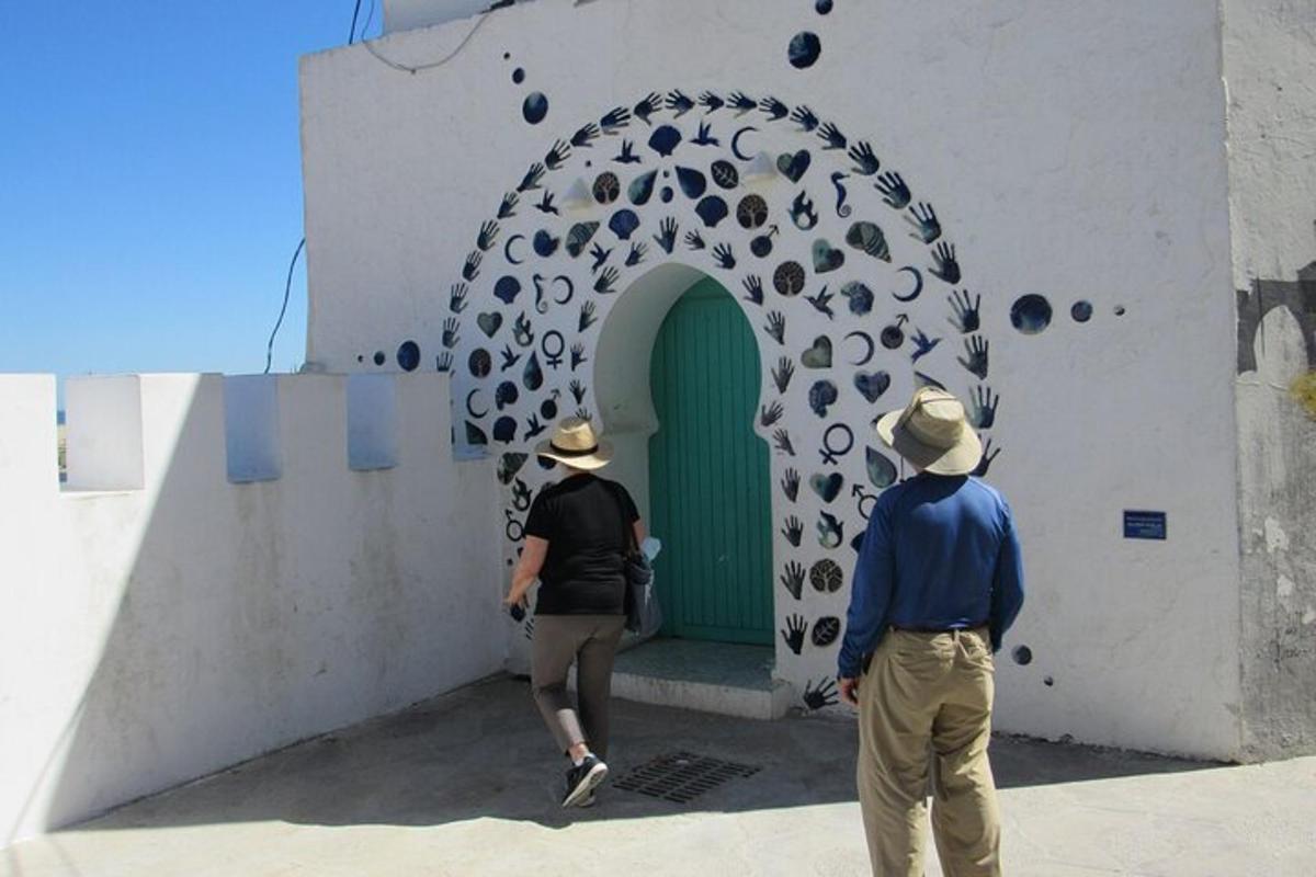 dues persones passejant per davant d'una porta verda en un edifici