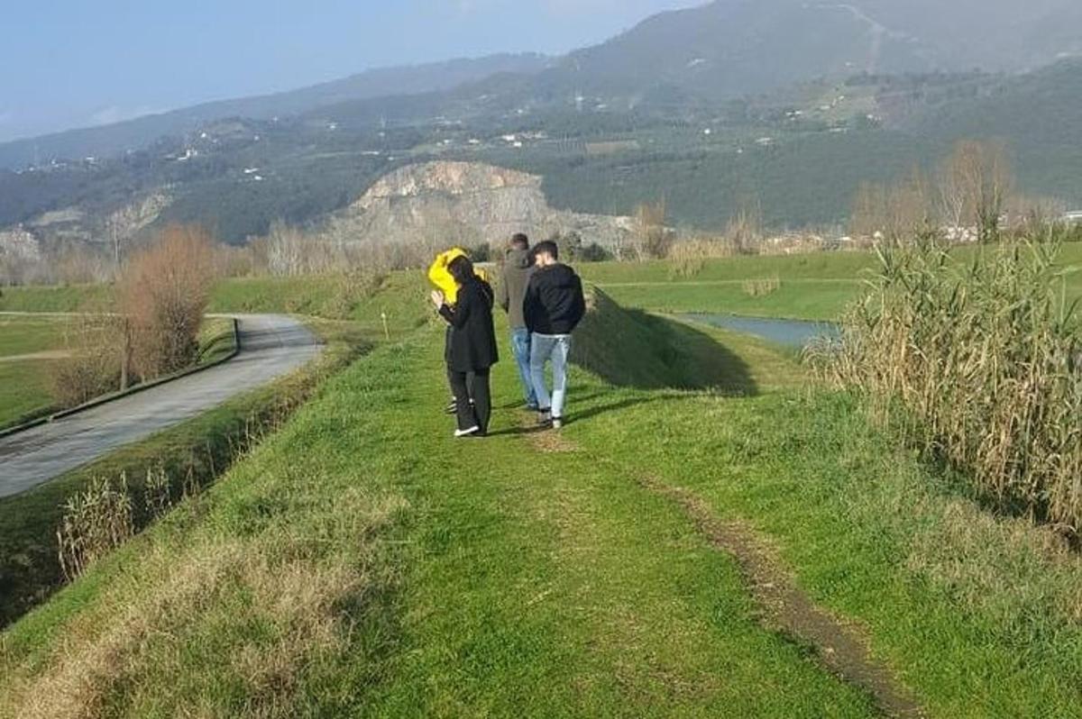 dvaja ľudia kráčajúci po ceste popri rieke