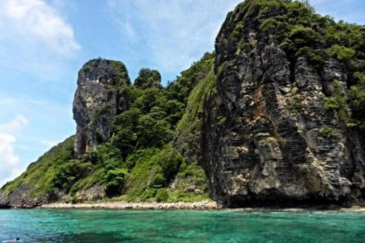 Una gran isla rocosa en el océano con agua azul.
