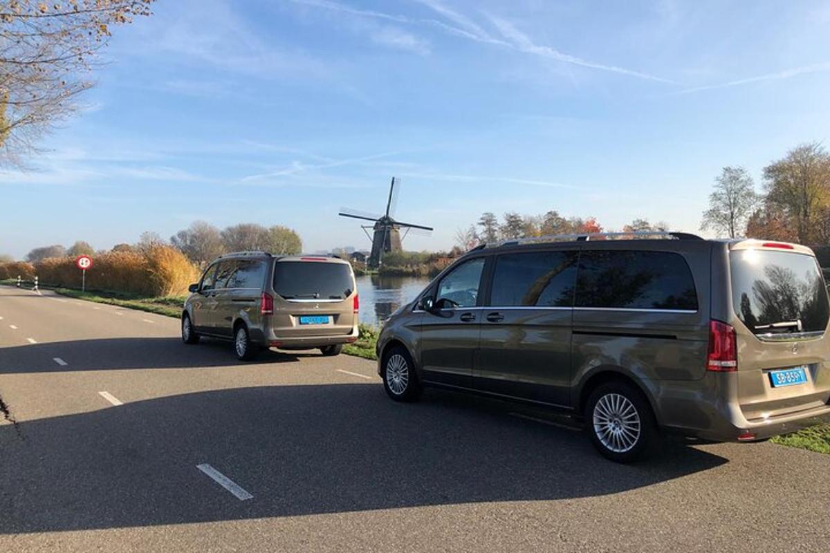 dois carros estacionados na beira de uma estrada com um moinho de vento