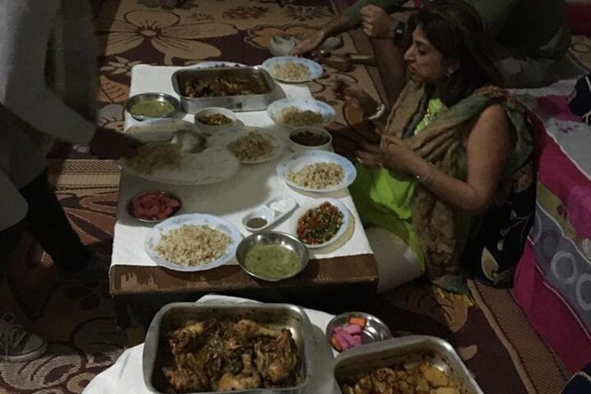 seorang wanita duduk di meja yang penuh dengan makanan