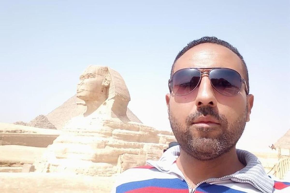 seorang lelaki memakai cermin mata hitam berdiri di hadapan sphinx