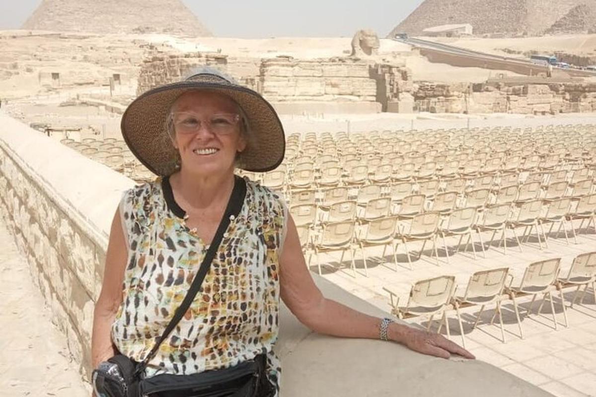 una donna con un cappello seduta davanti alle piramidi