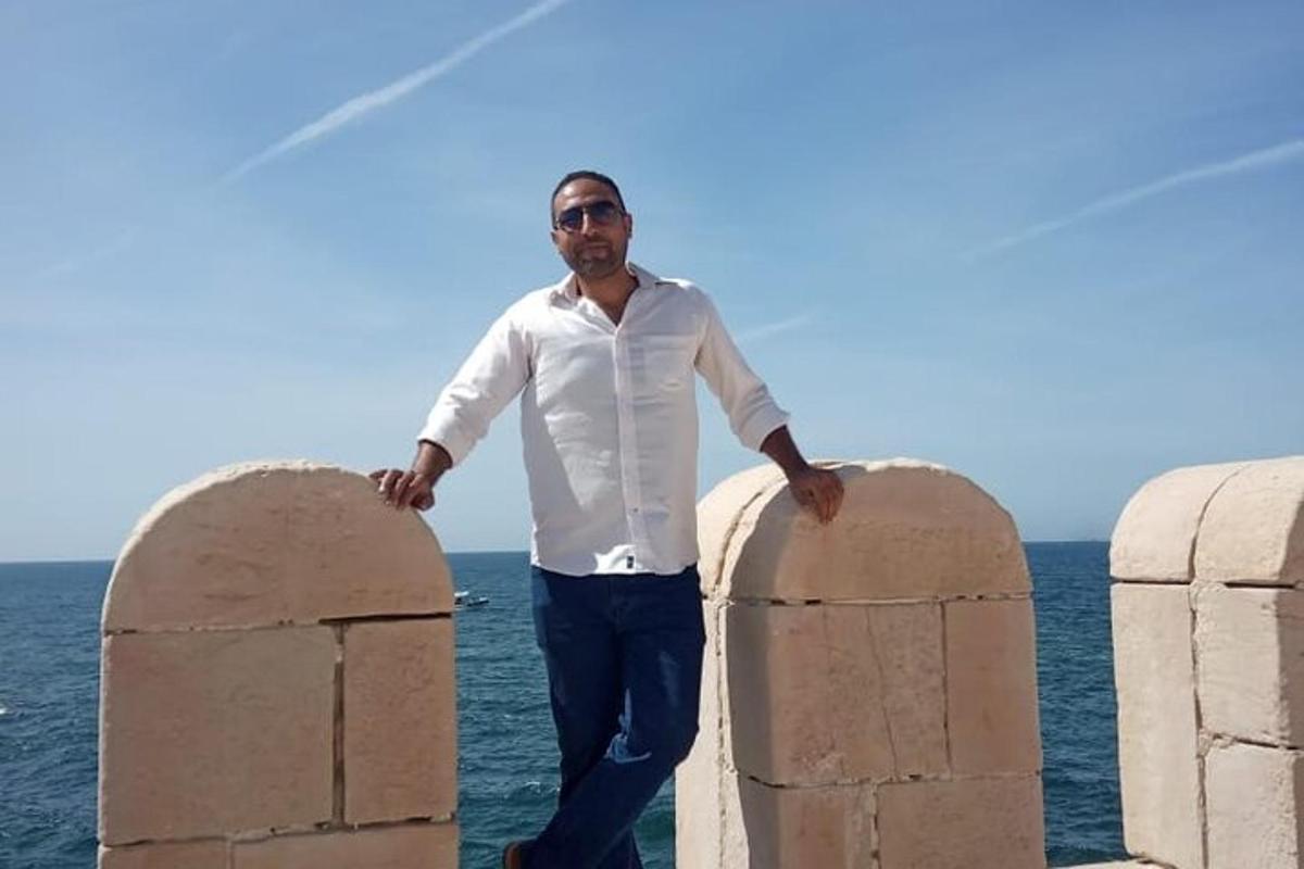 um homem parado entre duas barreiras de pedra perto do oceano