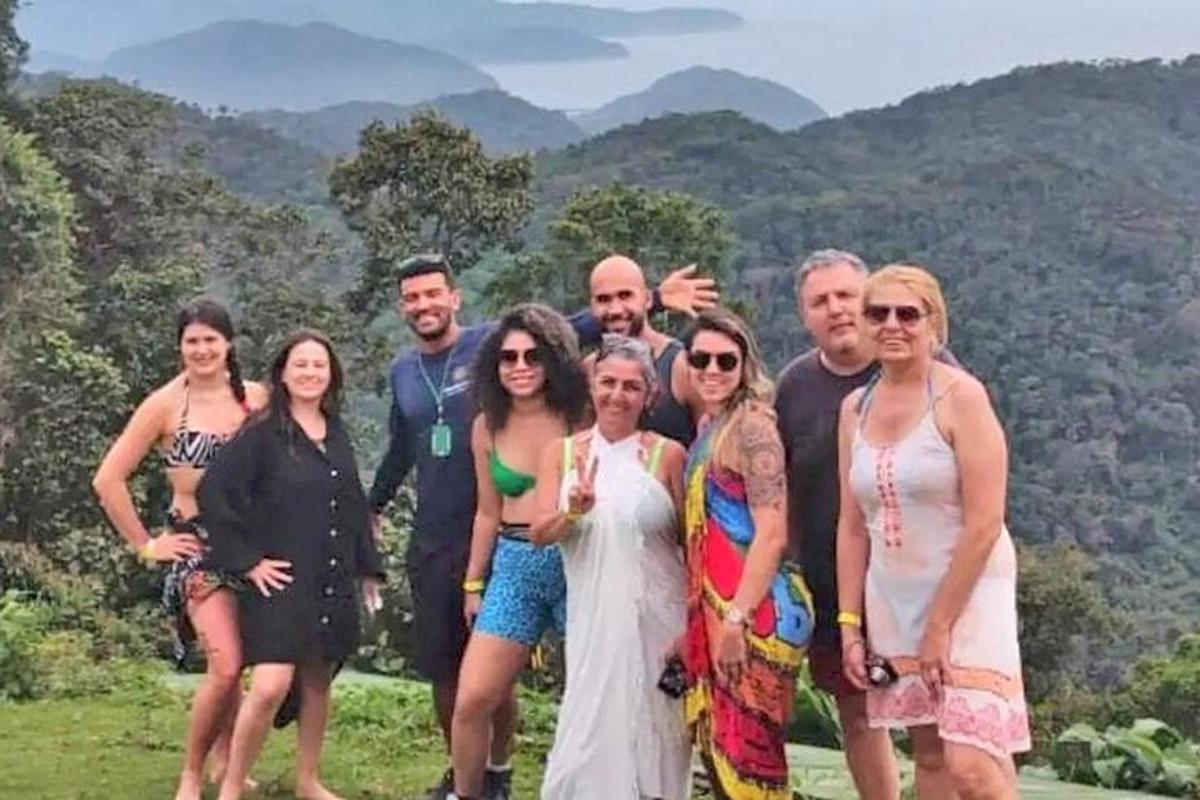 um grupo de pessoas posando para uma foto com montanhas ao fundo