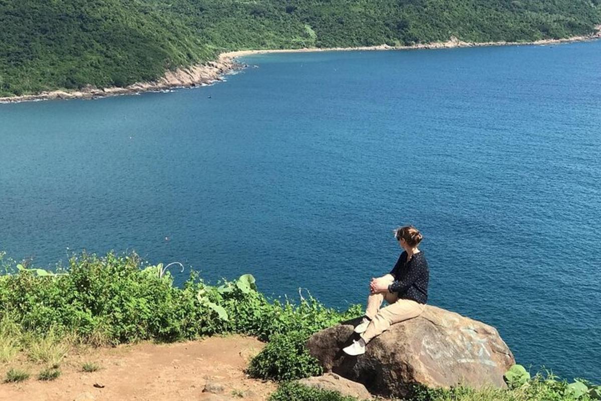 una dona asseguda en una roca amb vistes a una massa d'aigua