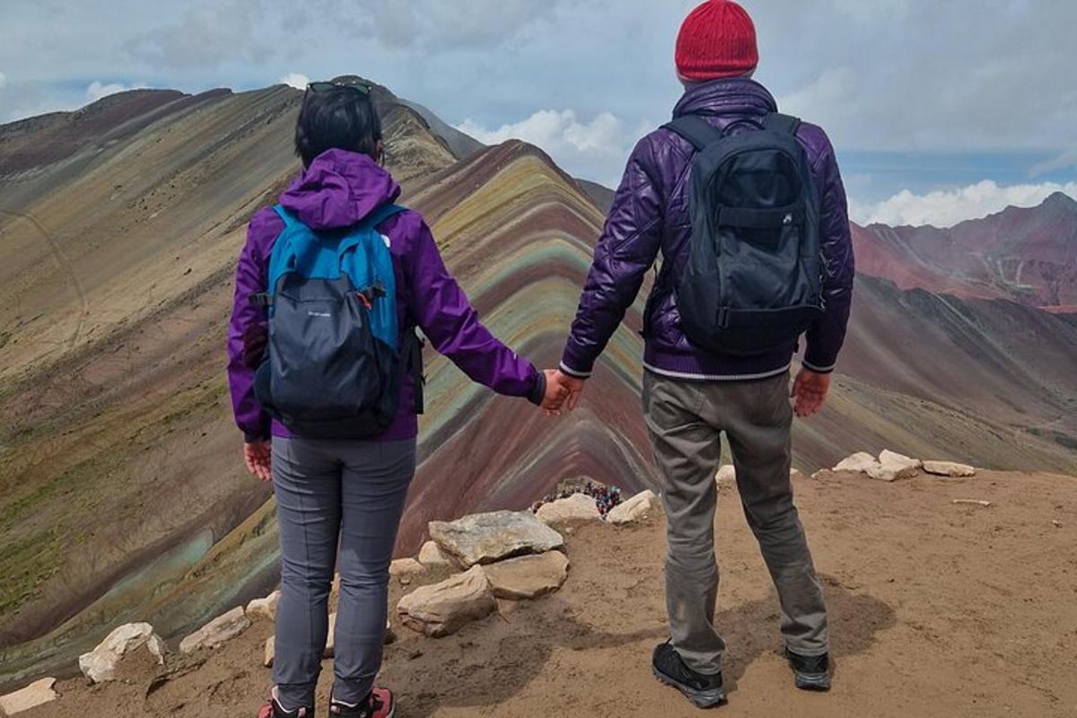 Dos personas tomadas de la mano mientras están de pie en la cima de una montaña