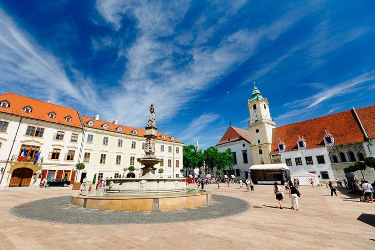 uma praça com uma fonte em frente a um edifício com uma torre do relógio