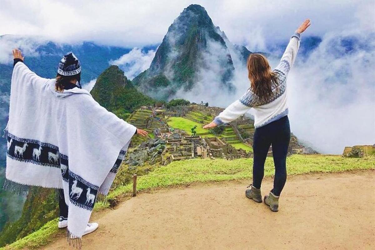 Dos personas de pie en la cima de una montaña con los brazos en alto.