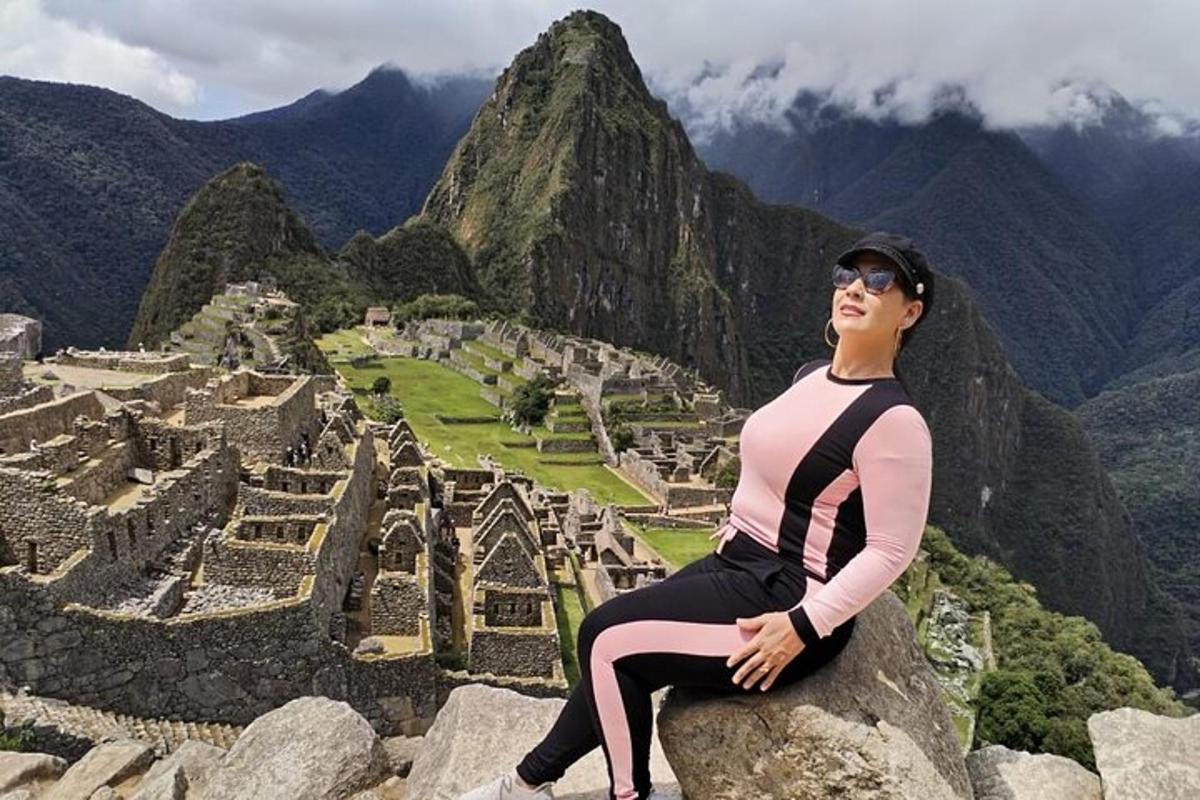 Una mujer sentada en una roca con vistas a las ruinas de una ciudad.