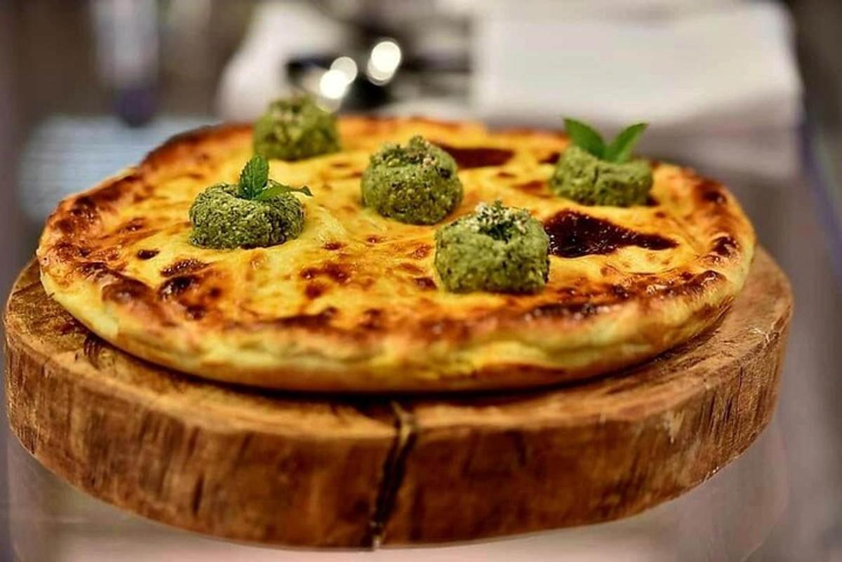 pizza yang terletak di atas papan pemotong kayu