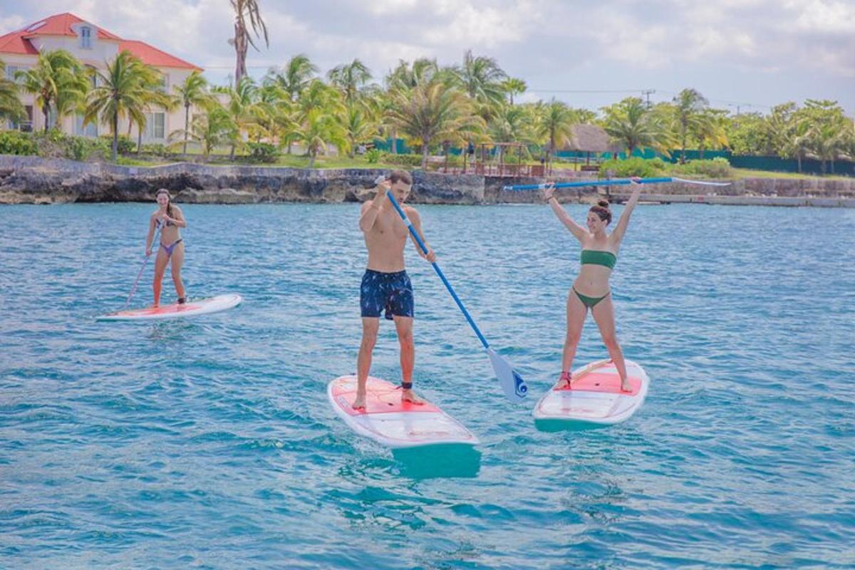 tres persones estan sobre taules de paddle surf a l'aigua