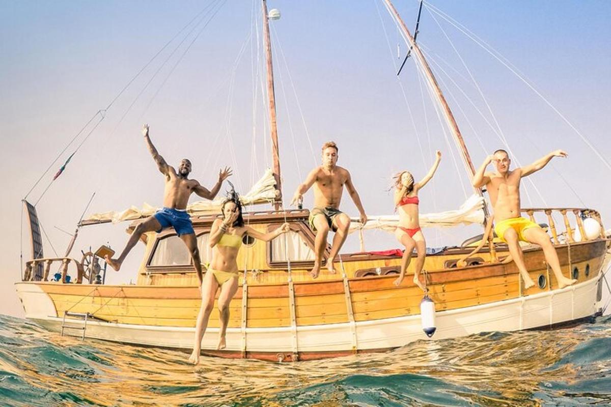 a group of people jumping off of a sailboat