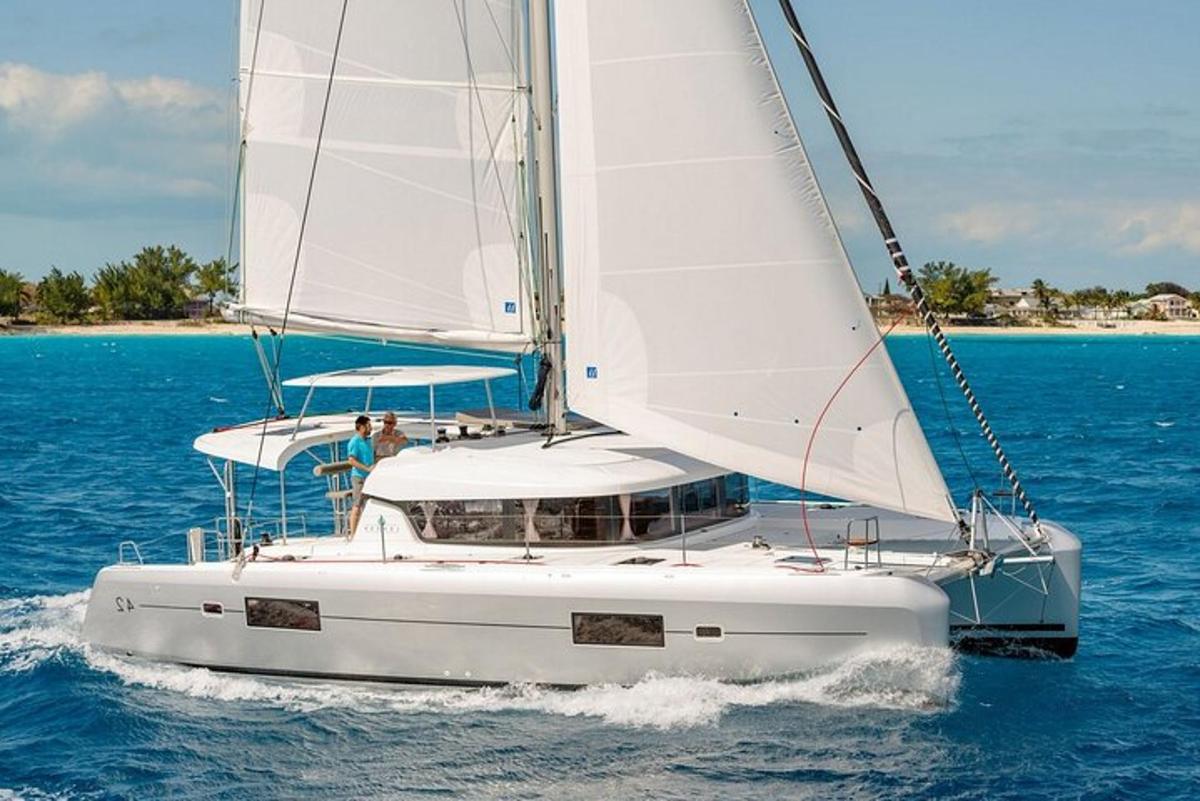 una barca a vela bianca sull'acqua con una spiaggia