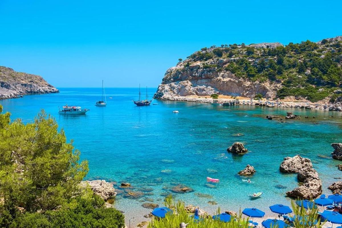 una platja amb para-sols blaus i barques a l'aigua