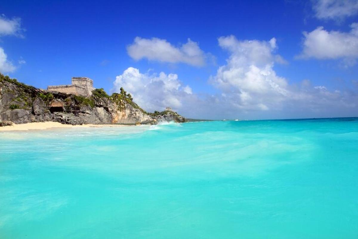 uma praia com água azul e um castelo ao fundo