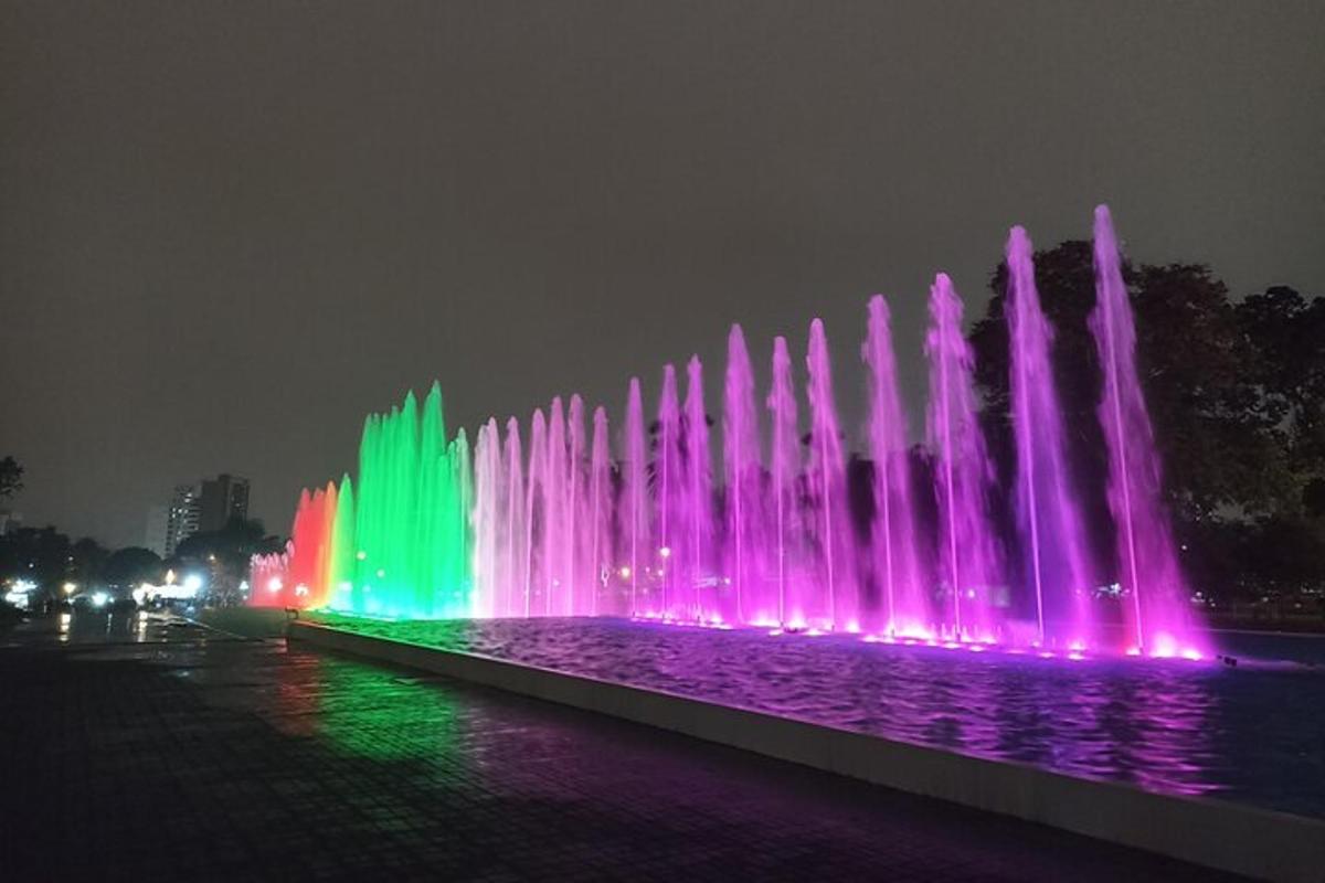 a water fountain is lit up in pink and green