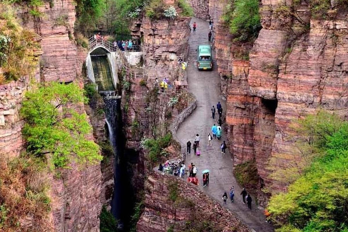 a group of people walking on a road through a canyon