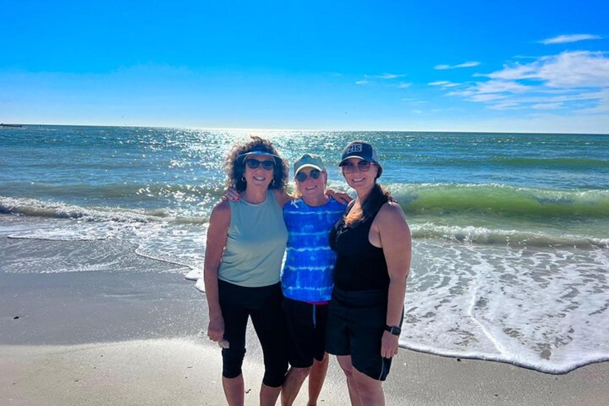 a group of three women standing on the beach