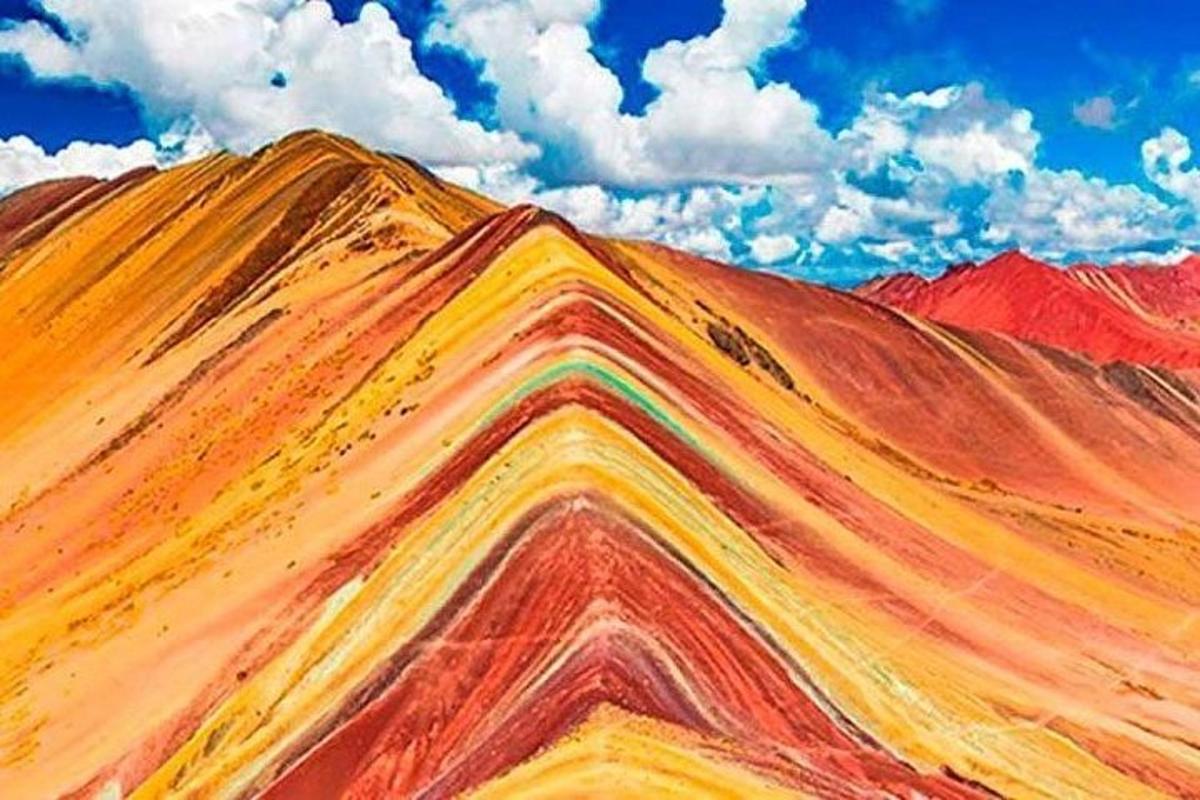 un dipinto di una montagna colorata sotto un cielo nuvoloso