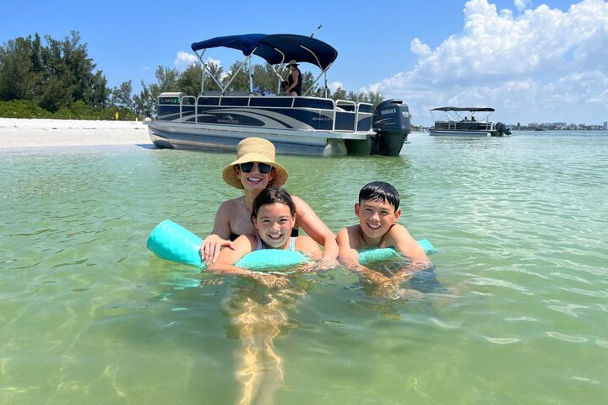 een vrouw en twee kinderen in het water met een boot