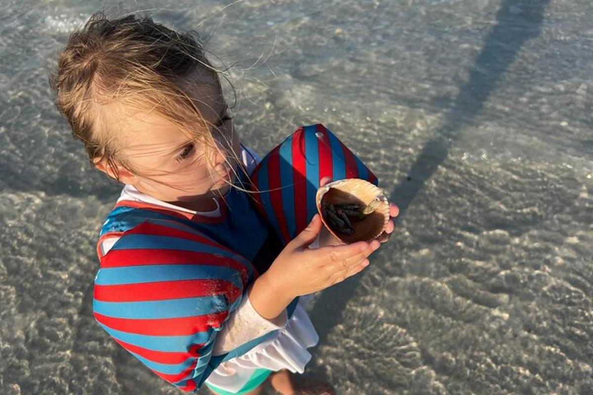een jong kind speelt met een bal op het strand