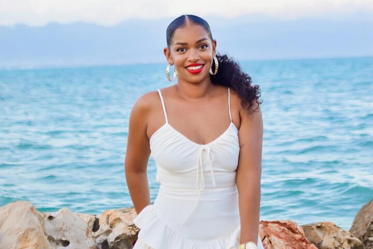 a woman in a white dress sitting on rocks by the water