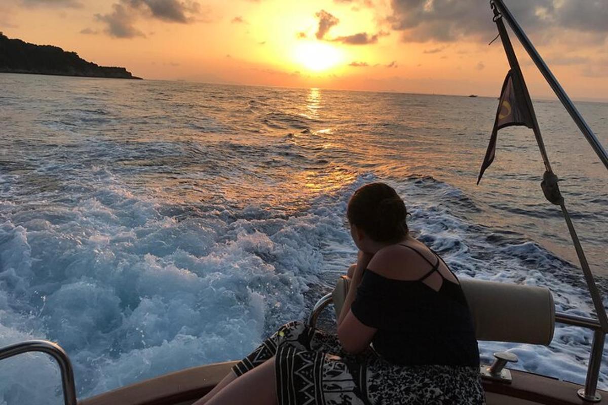 Μια γυναίκα που κάθεται σε μια βάρκα και παρακολουθεί το ηλιοβασίλεμα