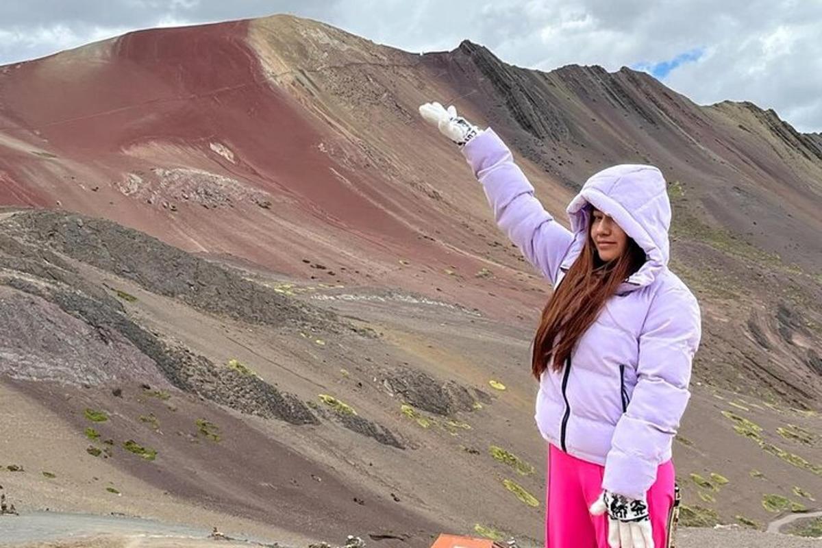 seorang wanita berdiri di atas bukit dengan tangannya di udara