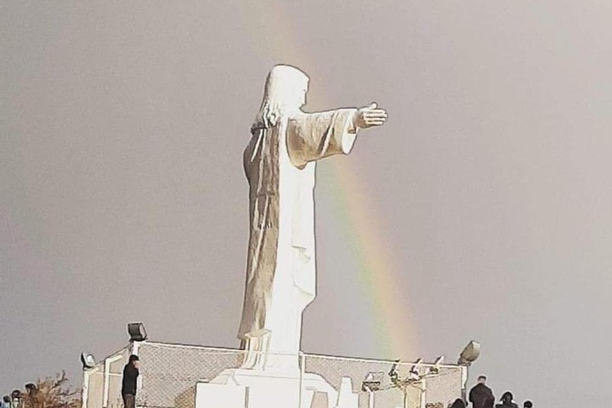 un arcobaleno davanti a una statua con un arcobaleno