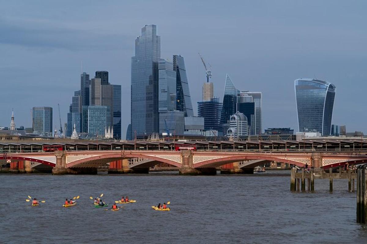 Un grupo de personas en kayaks en el agua cerca de un puente.