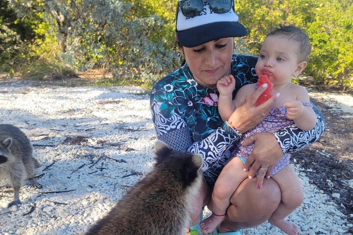 Una mujer sosteniendo a un bebé y alimentando a dos suricatas