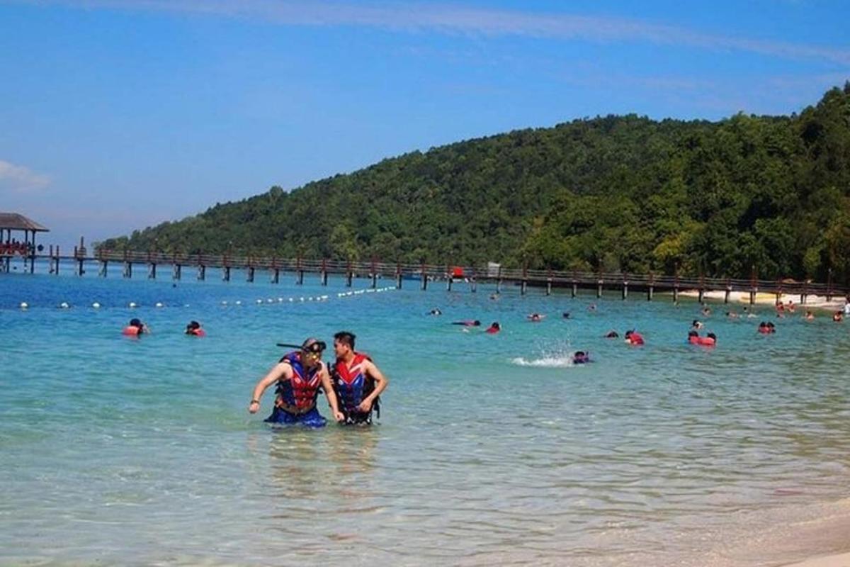 dues persones dempeus a l'aigua a la platja