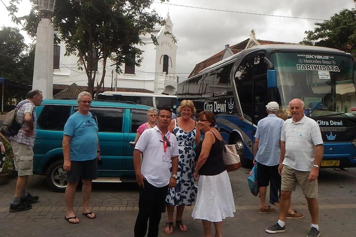 cilvēku grupa, kas stāv autobusa priekšā