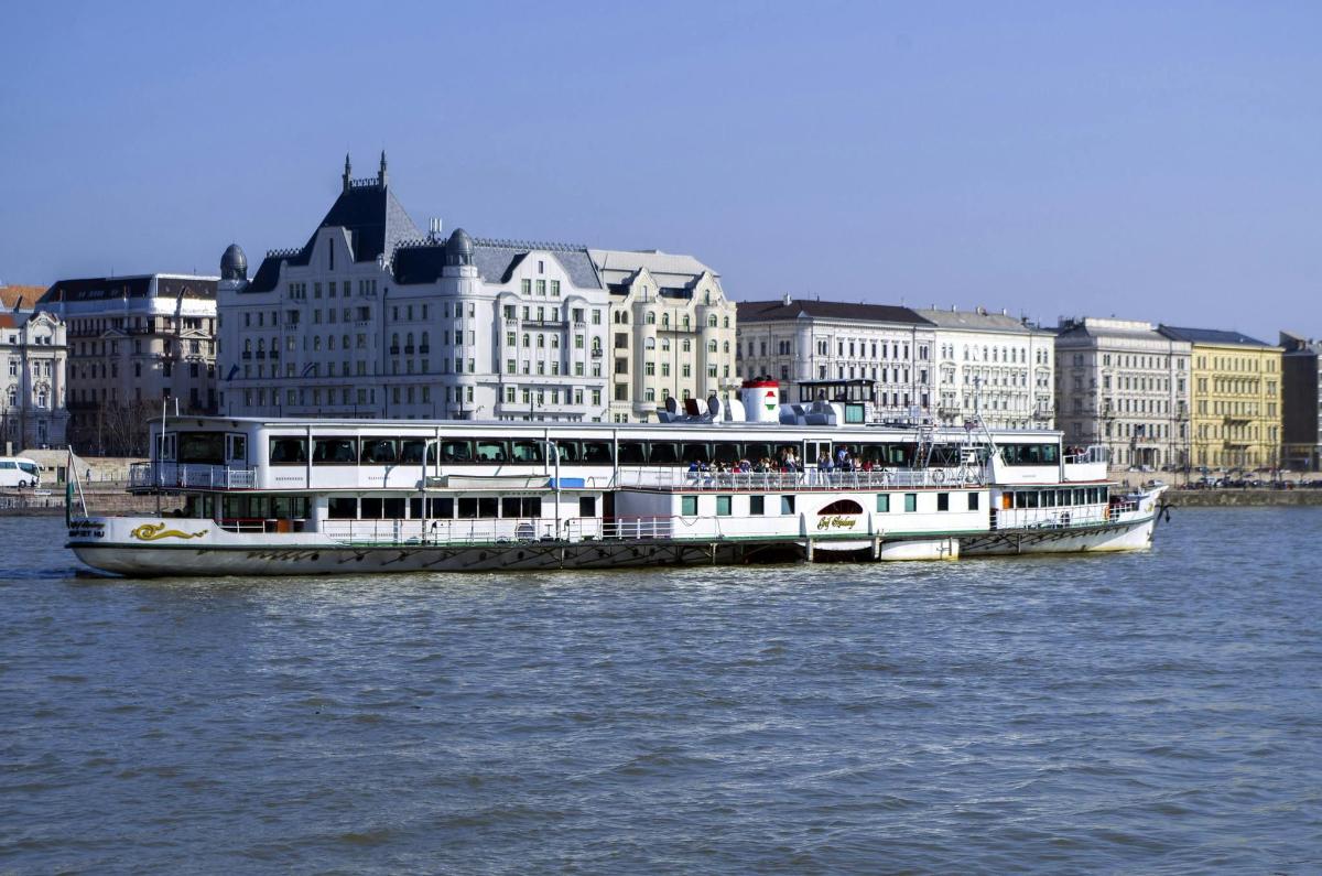 a large white boat on the water in front of buildings