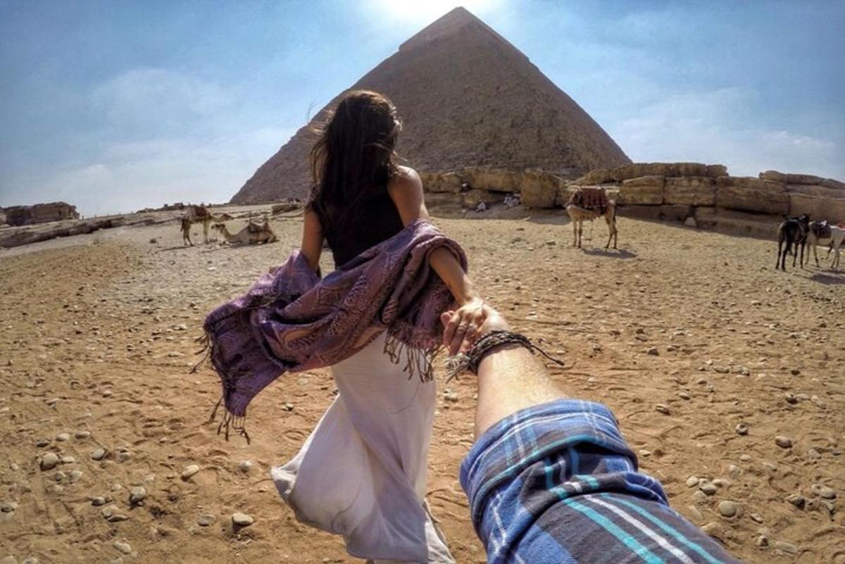 a woman holding onto the leg of a person looking at the pyramids