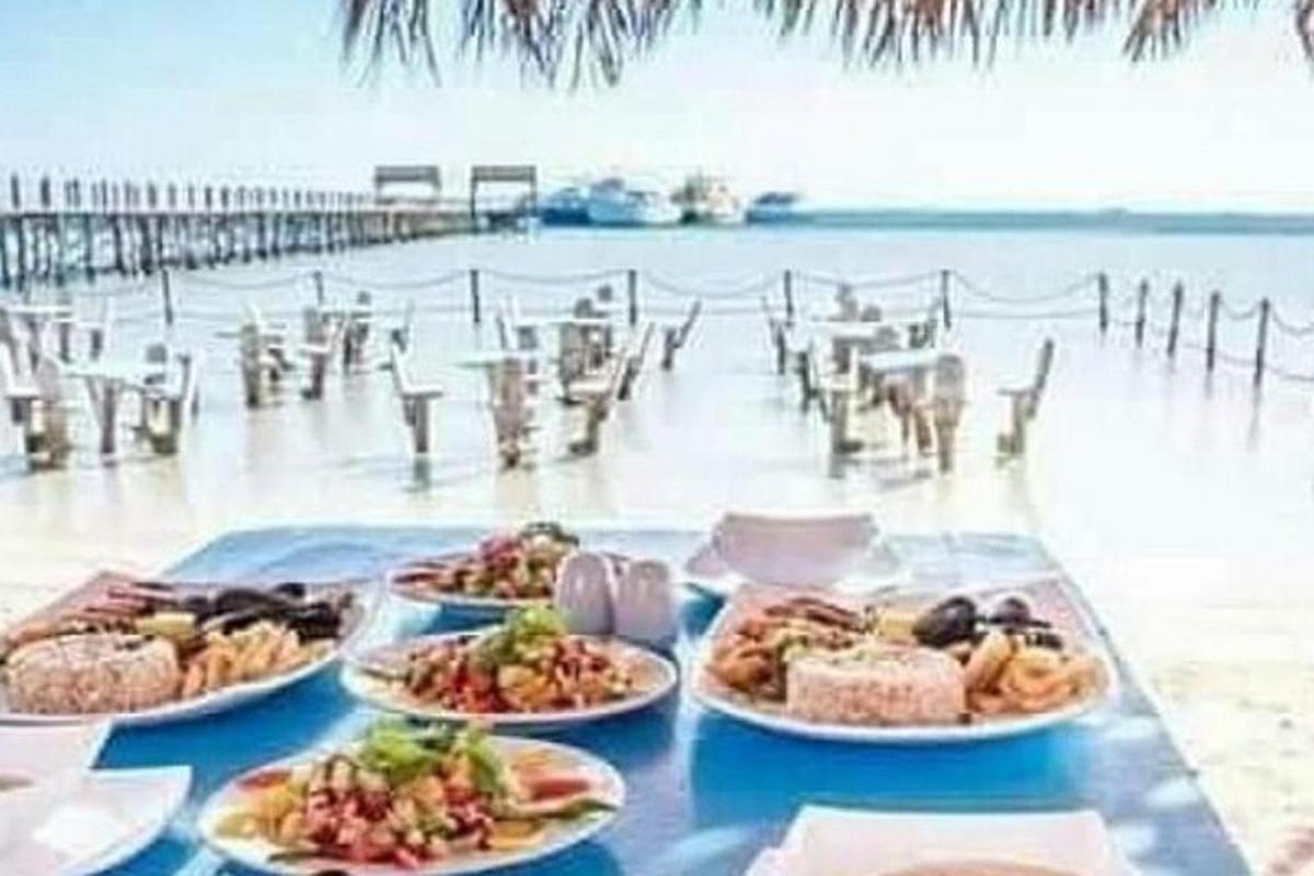a table with plates of food on a beach