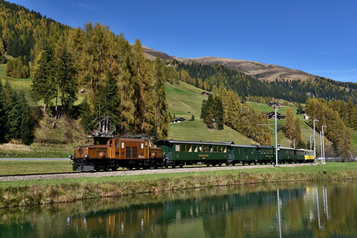 a train traveling down the tracks next to a river