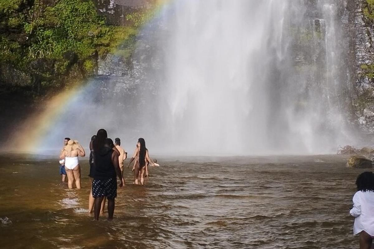 Un grupo de personas de pie en el agua frente a una cascada.