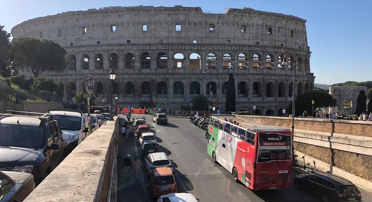 a red double decker bus in front of the coliseum